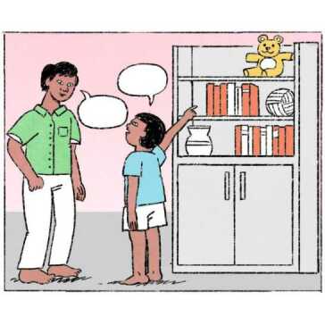 Un uomo in piedi accanto a una ragazza che indica un orsacchiotto sullo scaffale in alto.